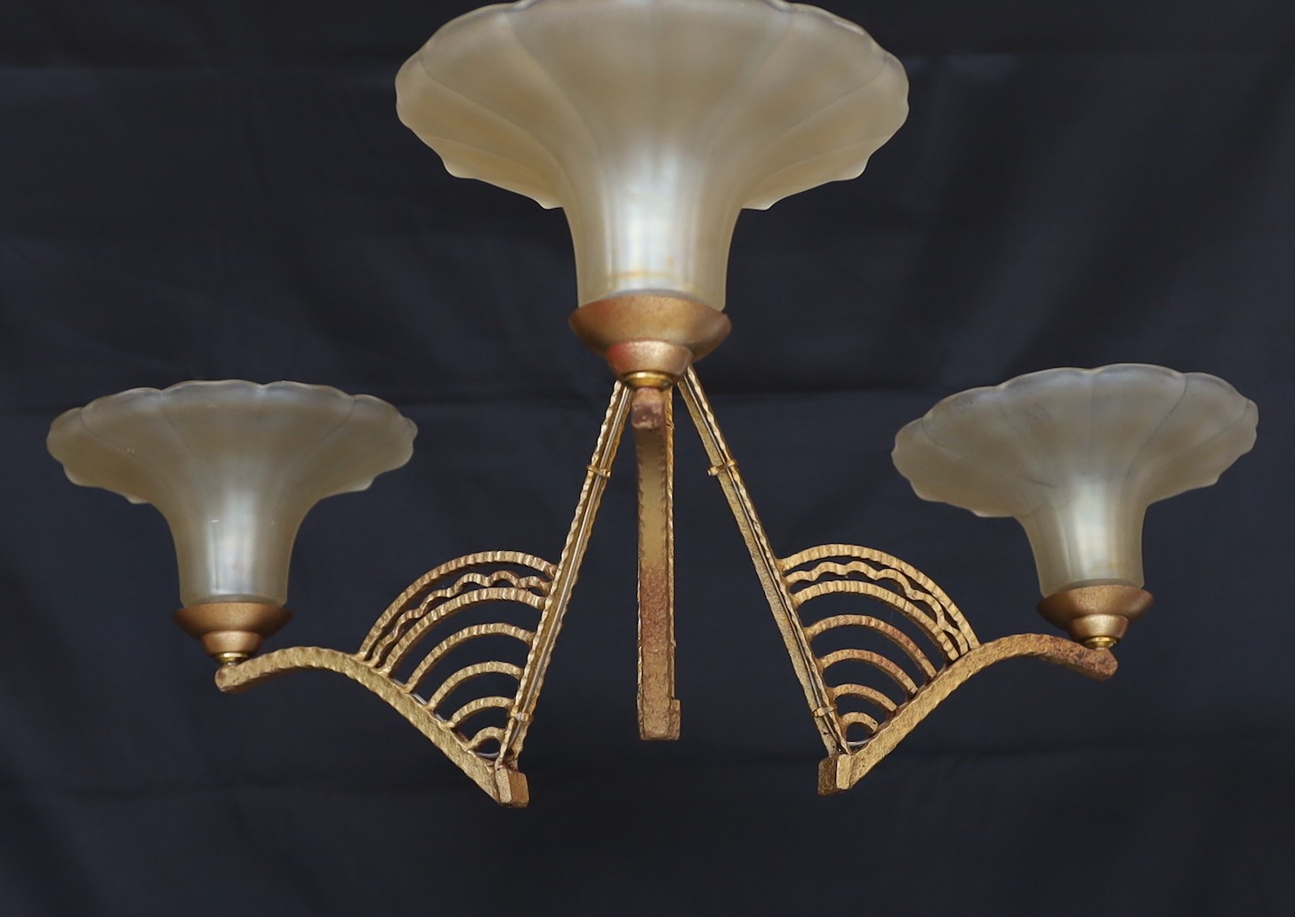 A 1920s French gold painted wrought iron light fitting with iridescent glass shades, height 62cm. width 68cm